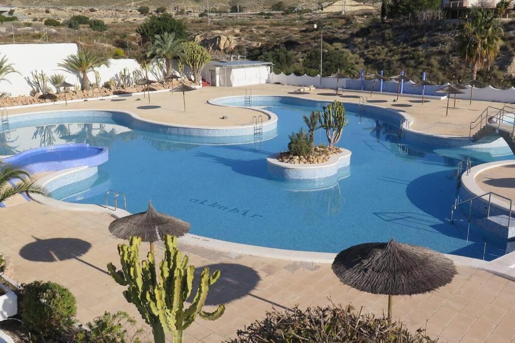 a large swimming pool with umbrellas in a resort at Bungalow in Moorse stijl in El Campello