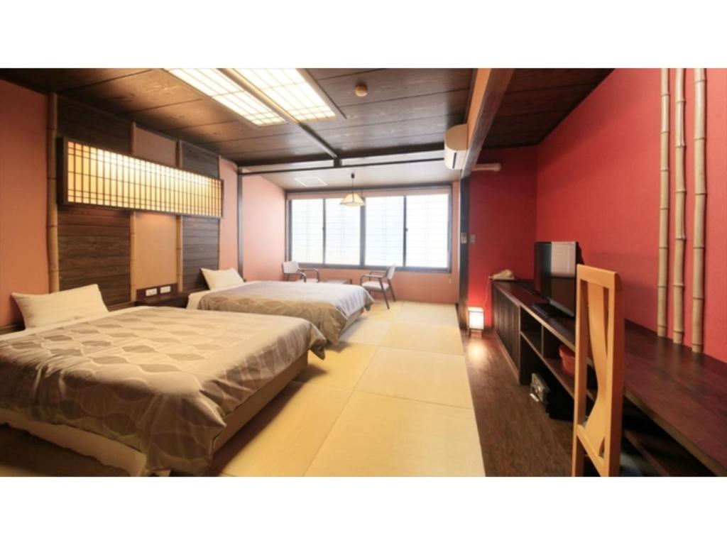 two beds in a room with red walls at Saikatei Jidaiya - Vacation STAY 96315v in Kaminoyama