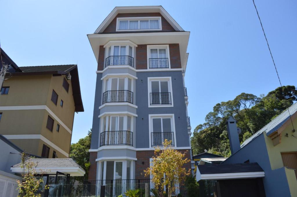 un edificio alto de color blanco con balcón negro en Rosa Edifício Van Gogh, en Gramado