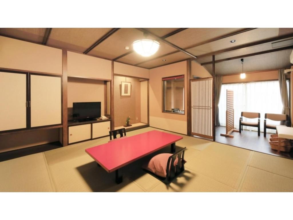 Zimmer mit einem roten Tisch und einem Wohnzimmer in der Unterkunft Saikatei Jidaiya - Vacation STAY 96456v in Kaminoyama
