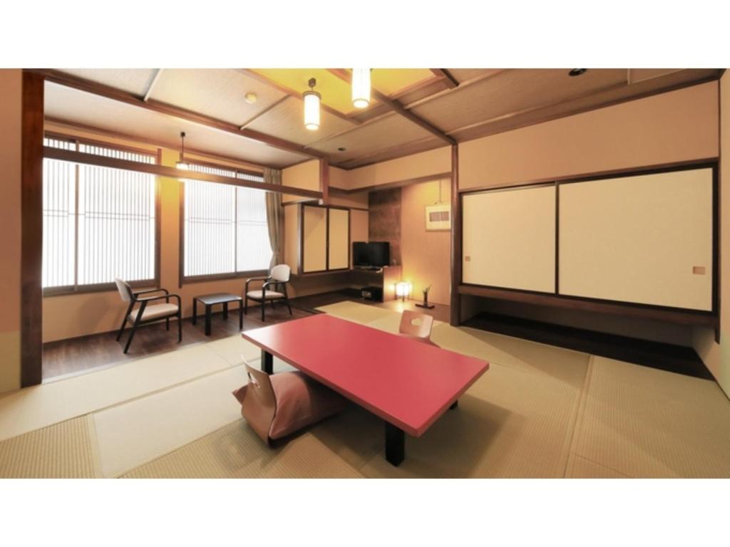 Habitación grande con mesa roja y sillas. en Saikatei Jidaiya - Vacation STAY 96429v, en Kaminoyama