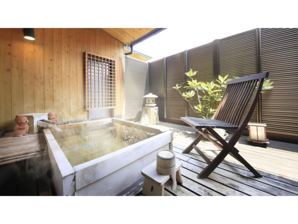 einen Stuhl und eine Badewanne auf einer Holzterrasse in der Unterkunft Saikatei Jidaiya - Vacation STAY 96435v in Kaminoyama