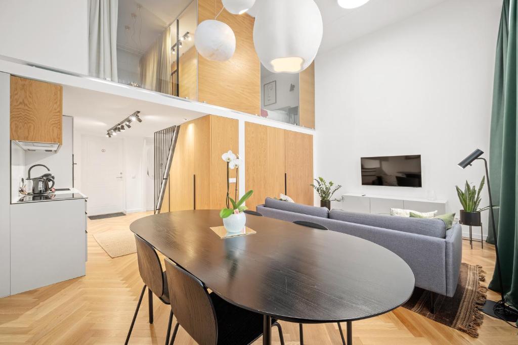 a kitchen and living room with a table and a couch at Owl Jazz Apartments - luxury apartments in the heart of the city in Kaunas