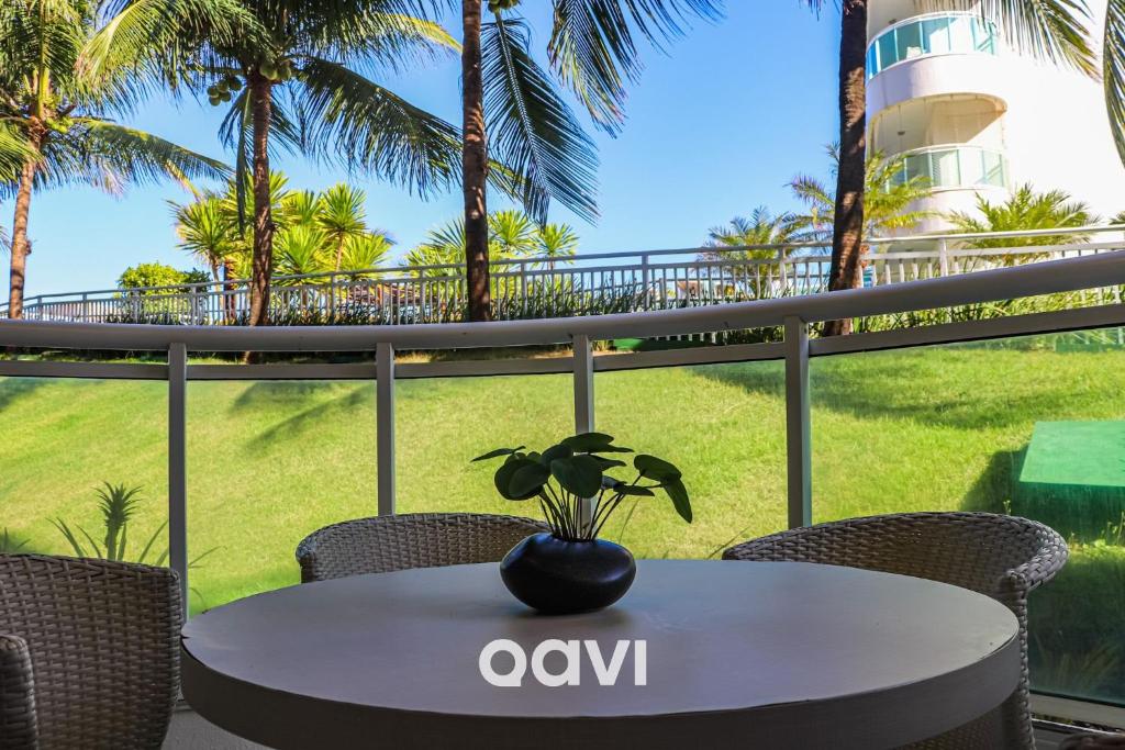 a table and chairs on a balcony with palm trees at Qavi - Apto em Resort Beira Mar Cotovelo #InMare43 in Parnamirim