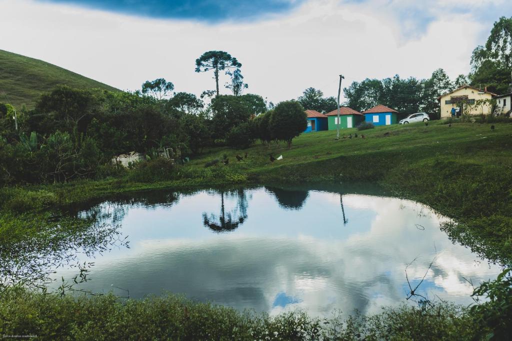 um lago num campo com casas ao fundo em Fazenda Alegria em Ouro Preto