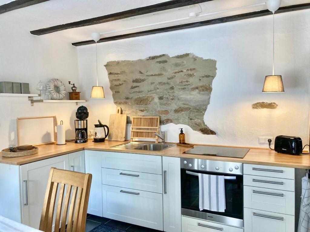 a kitchen with white cabinets and a sink at Ferienhaus Goldstück wohnen im Weinberg in Pommern