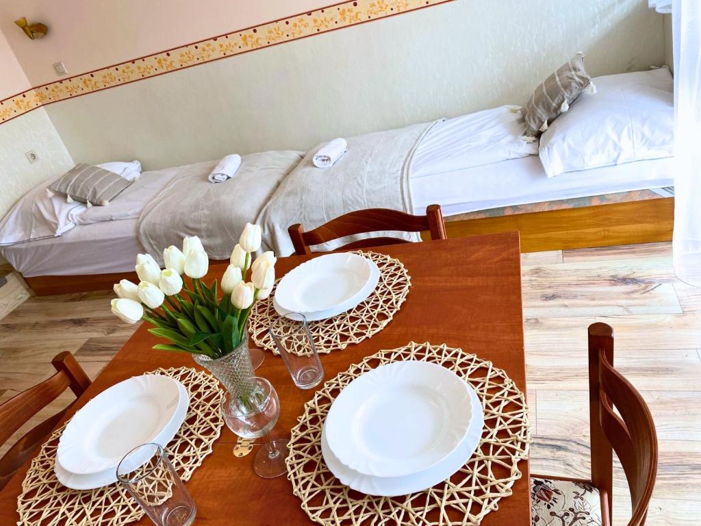 mesa de comedor con 2 platos y 1 cama en Mikszáth Apartman, en Balatonfüred