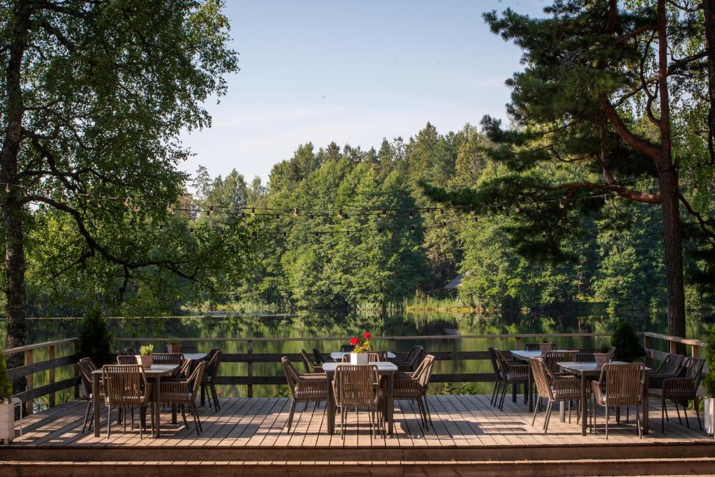 a patio with tables and chairs next to a lake at Saarjärve Puhkemaja 32-le, 8 magamistuba in Tromsi
