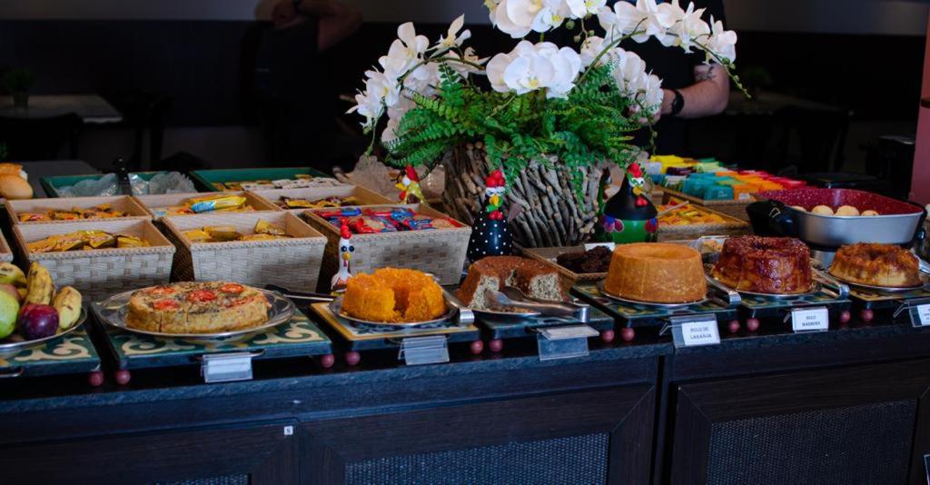 un buffet lleno de diferentes tipos de pasteles y tartas en Hotel Imperatriz, en Telêmaco Borba