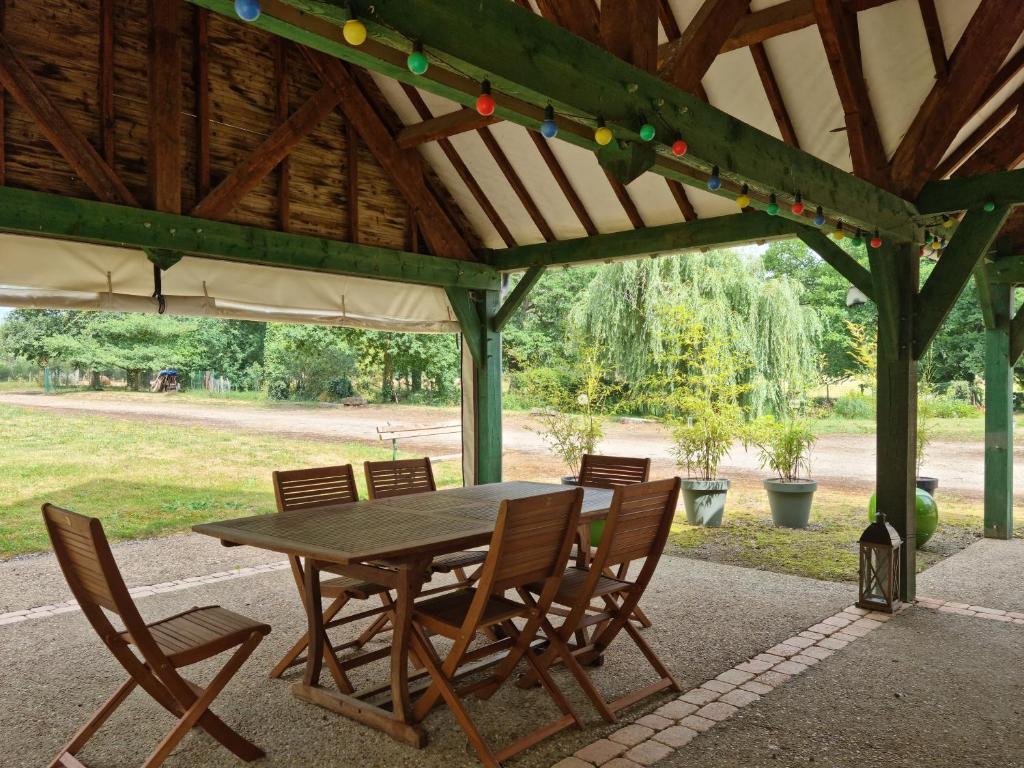 a wooden table and chairs under a pavilion at L &#39;Aupinouse Chambre double Pivoine avec salle d&#39;eau privative in La Suze-sur-Sarthe