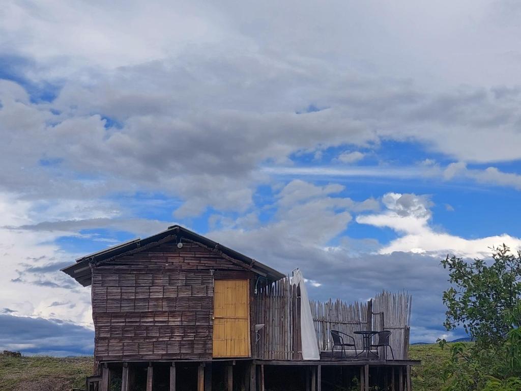 eine alte Holzhütte mit einem Zaun und Himmel in der Unterkunft Hotel Flor de Liz Bereshit Bara in Villavieja