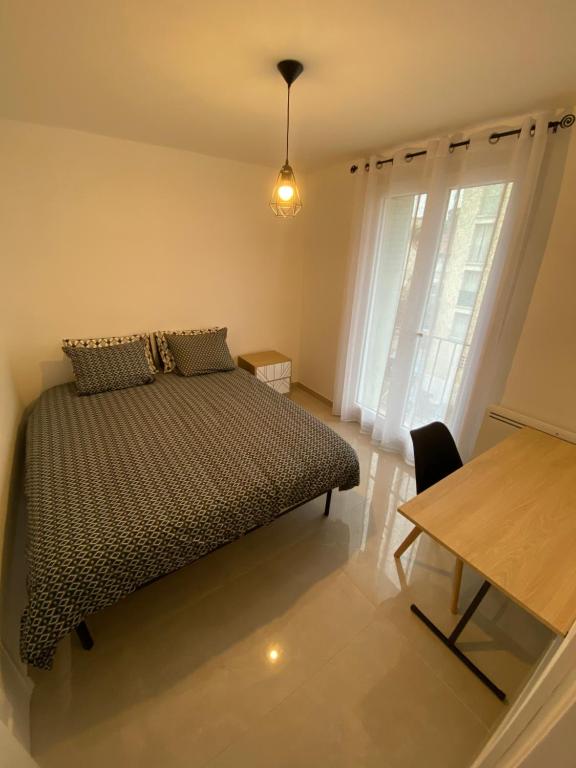 - une chambre avec un lit, une table et une fenêtre dans l'établissement Un T3 chaleureux à proximité du Dôme et du métro, à Marseille
