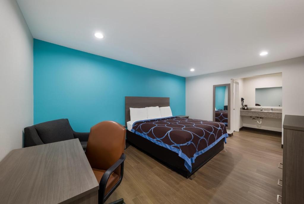 Rodeway Inn في ويتشيتا فولز: غرفة نوم بسرير وجدار ازرق