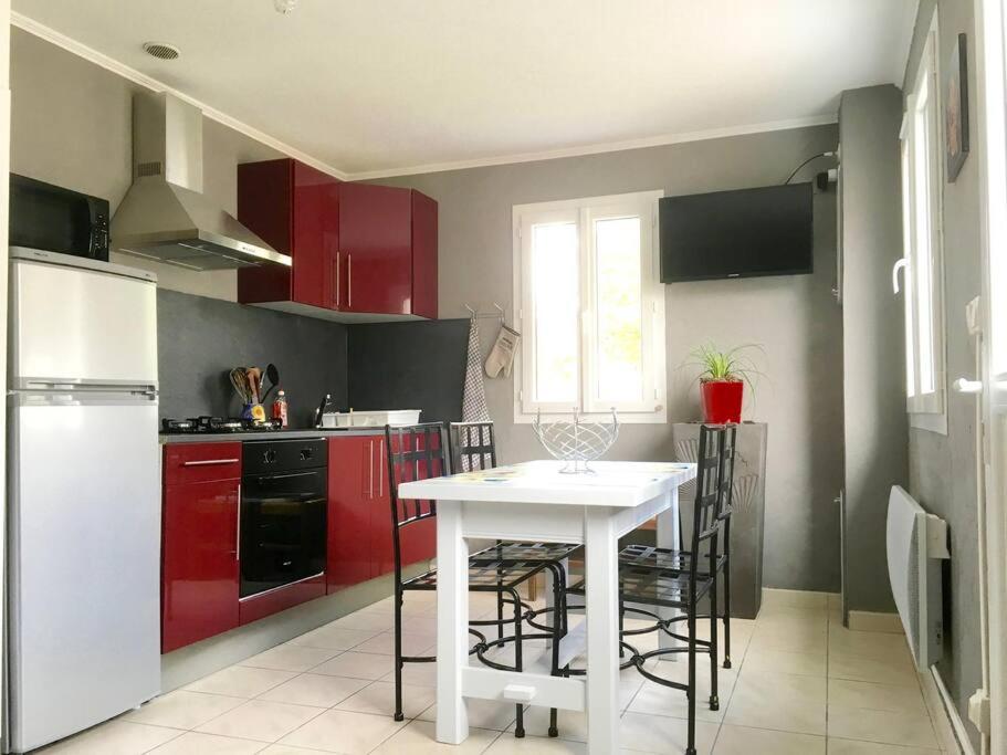 een keuken met een witte tafel en rode kasten bij gite le ptit bleu maison totalement indépendant in La Tremblade