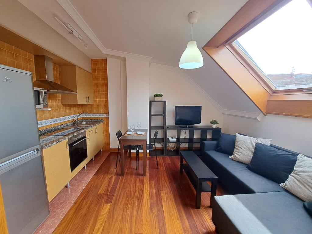 a living room with a blue couch and a kitchen at Vigo centro, ático. in Vigo