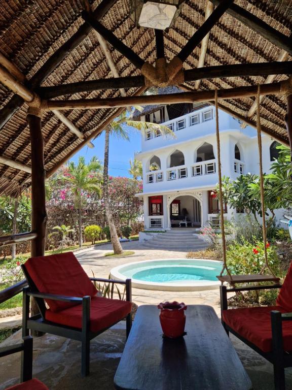 a patio with a table and chairs and a house at Waridi House in Watamu
