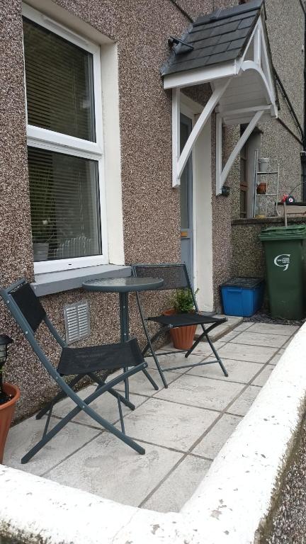 Un patio con una mesa y sillas al lado de un edificio. en Cosy Mews House Close to Harbour, en Porthmadog