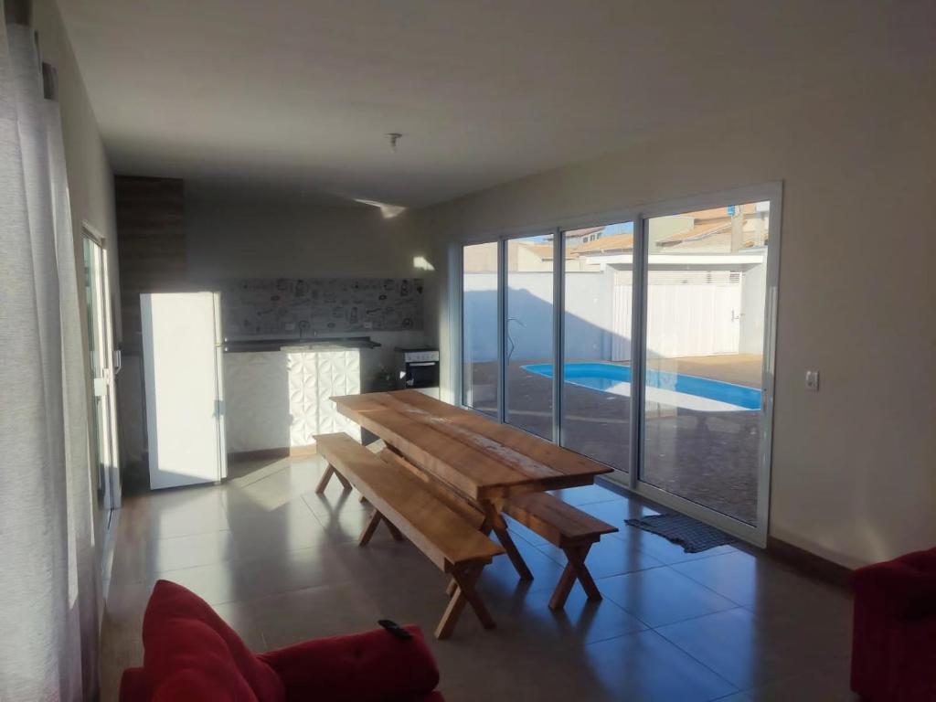 einen Holztisch in einem Zimmer mit einem großen Fenster in der Unterkunft Casa Lazer com piscina in Brotas