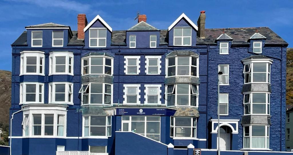 un grand bâtiment bleu avec des fenêtres blanches dans l'établissement The Sandbanks, à Barmouth