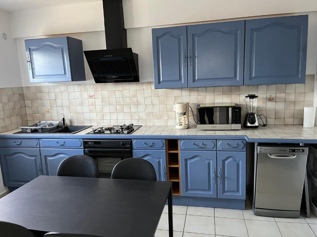 a kitchen with blue cabinets and a stove top oven at Les oliviers in Juvignac
