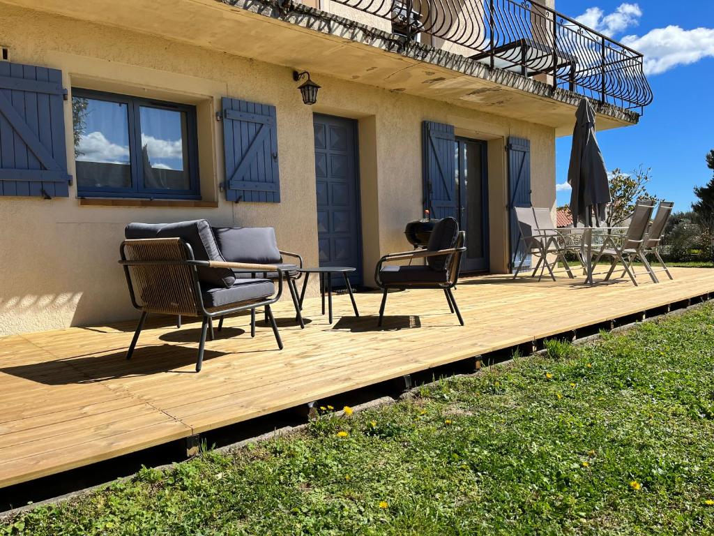 a wooden deck with chairs and a table on it at Les oliviers in Juvignac