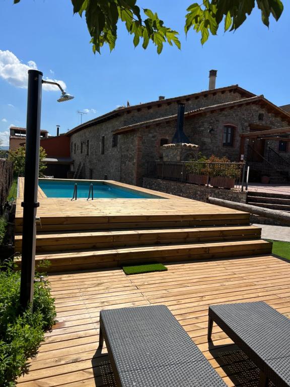 a swimming pool with wooden steps and two benches at Ca La Gràcia in Cabrianas