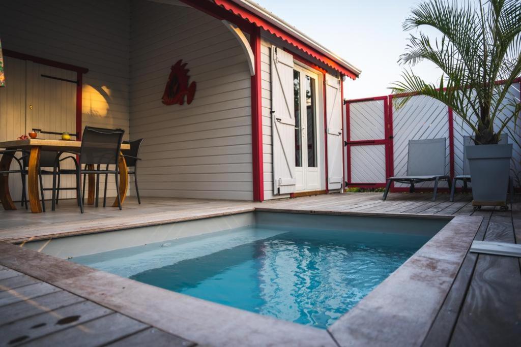 德賽的住宿－Caraïbes Cottage Grenat piscine privée 900m de Grande anse，游泳池毗邻带桌子的房子