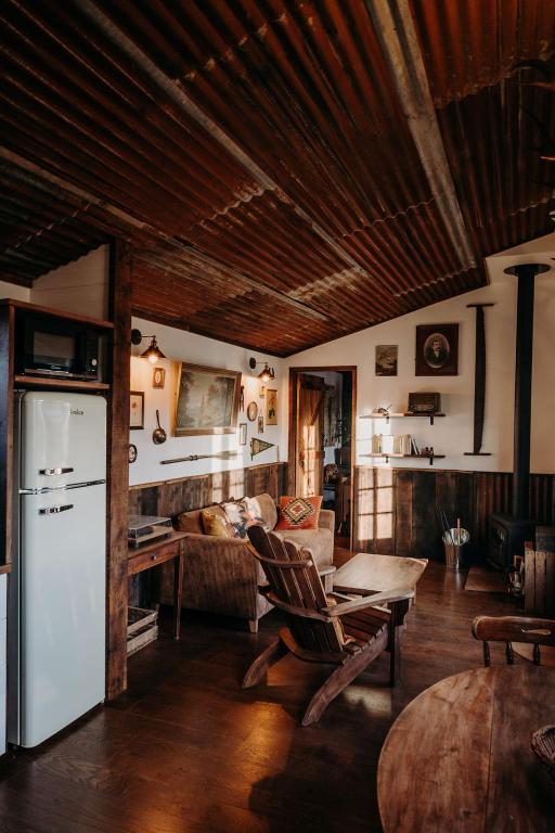 - un salon avec un réfrigérateur blanc et une table dans l'établissement La ferme du pont de Maumy, cabane au bord de l'étang et bain nordique, à Busserolles