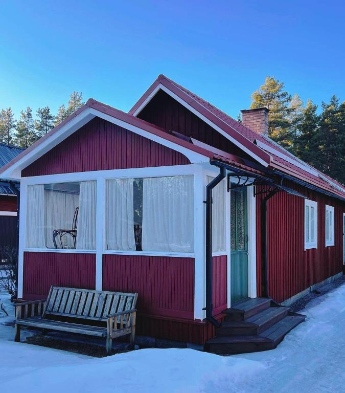 una casa roja con un banco delante en Stuga i Furudal (nära Rättvik), en Furudal