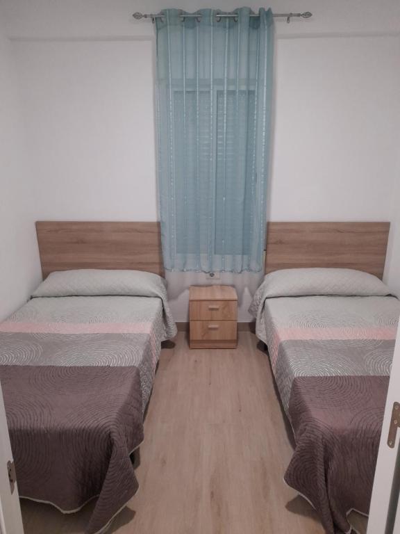 a bedroom with two beds and a blue curtain at Apartamentos playa de bellreguard,gandia,oliva,denia,benidorm in Bellreguart