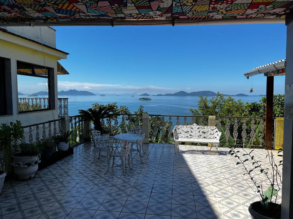 a patio with a table and a bench and the ocean at Castelinho de Ibicuí in Mangaratiba
