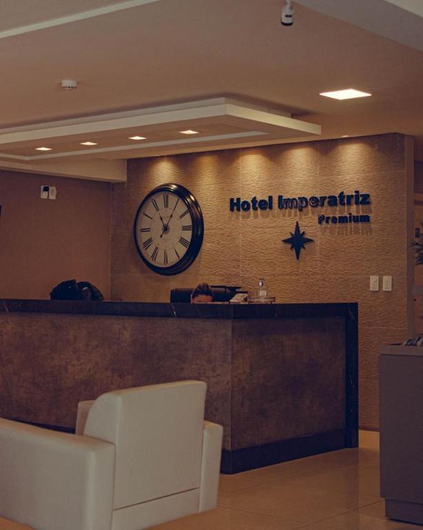 Un vestíbulo de hotel con un reloj en la pared en Hotel Imperatriz Premium, en Telêmaco Borba