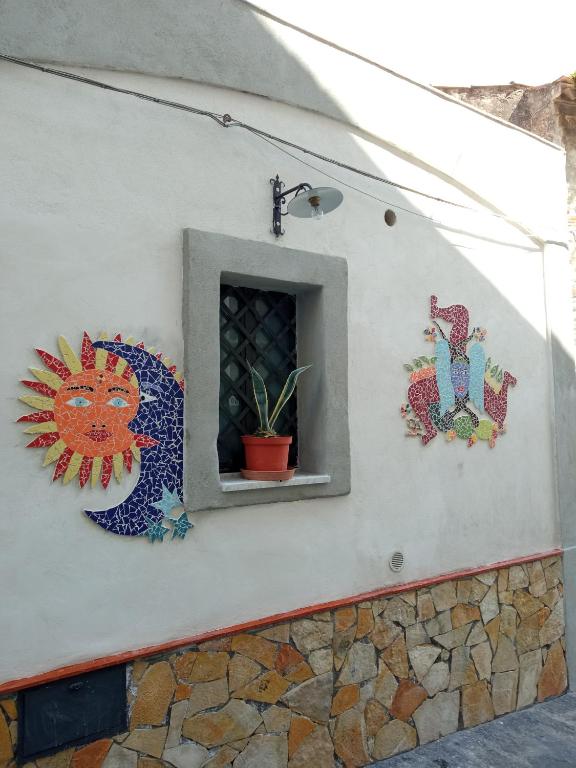 un mur avec une fenêtre avec un chat et une plante dans l'établissement Etnalcantara, à Castiglione di Sicilia