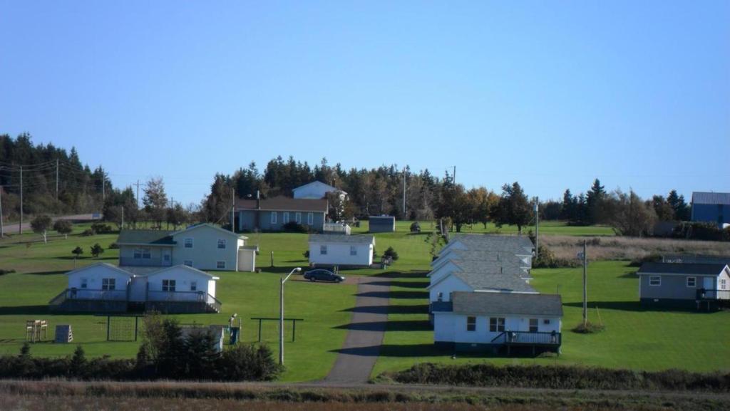 a group of houses in a field with trees at Mayfield Country Cottages in Cavendish