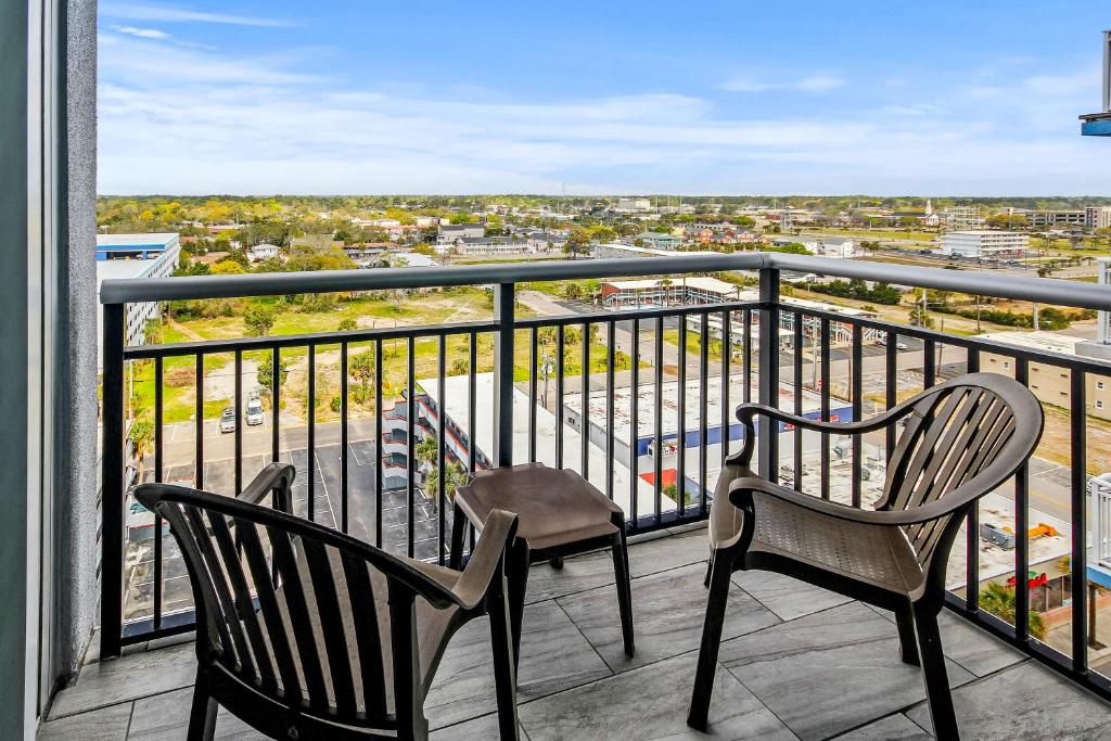 a balcony with two chairs and a view of a city at The Splendid South Carolina Getaway in Myrtle Beach