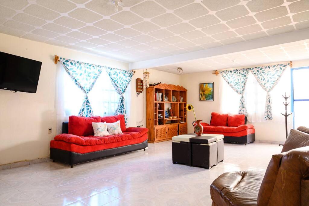 een woonkamer met twee rode banken en een tv bij Casa Hogareña y Artística in Carrillo