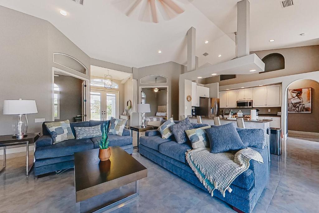 uma sala de estar com sofás azuis e uma cozinha em Palmetto Canal em Cape Coral