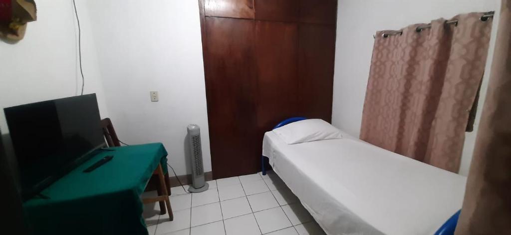 Habitación hospitalaria pequeña con cama y escritorio en Duerme tranquilo, en Alajuela