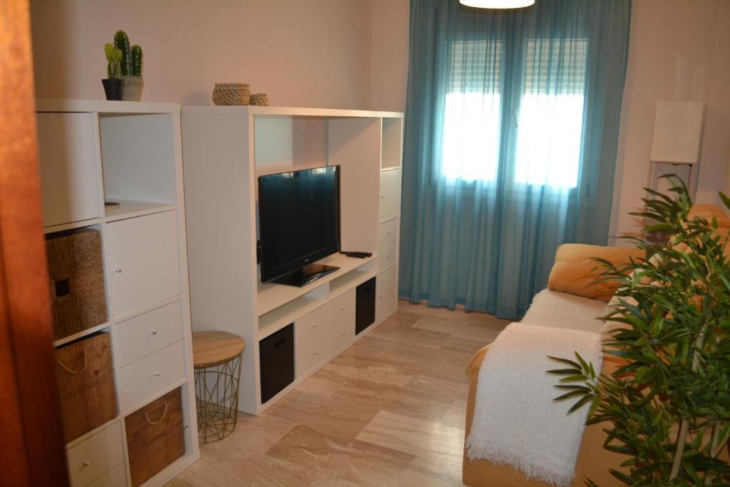 - un salon avec un canapé et une télévision dans l'établissement Apartamento Posidonia Free Parking, à Cadix
