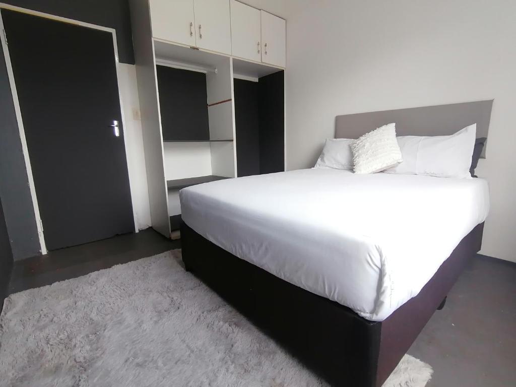a bedroom with a large bed with white sheets and pillows at Budget Room in Pietermaritzburg