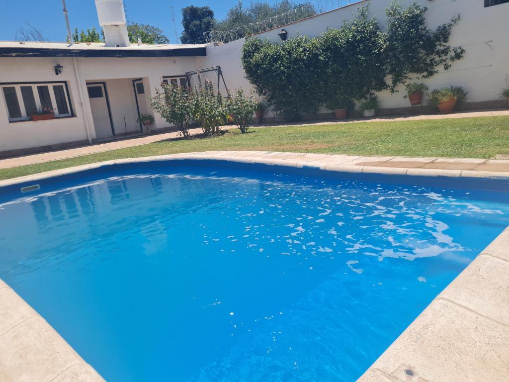 a large blue swimming pool in front of a house at MENDOZA TURiSTA - CASA EN SAN MARTÍN, MENDOZA "ANTONIO's HOUSE" in San Martín