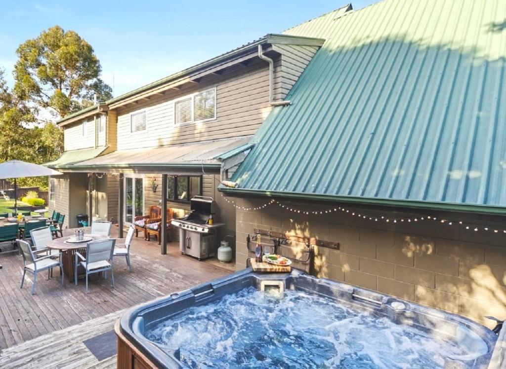 a hot tub on a deck next to a house at Botanical HideAway Taupo in Taupo