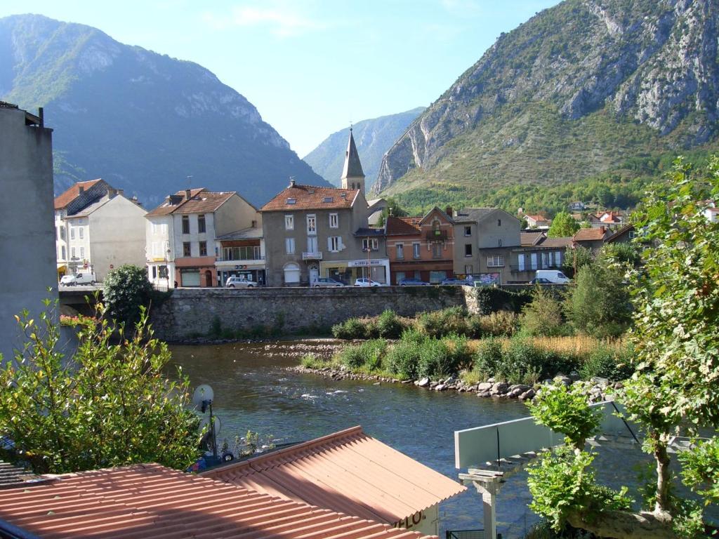 une ville sur une rivière avec des montagnes en arrière-plan dans l'établissement Logis Hôtel Restaurant de la Poste, à Tarascon-sur-Ariège
