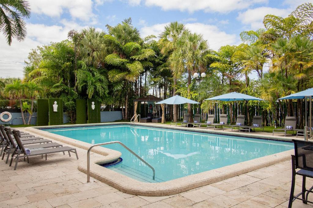 a large swimming pool with chairs and umbrellas at Regency Miami Airport by Sonesta in Miami