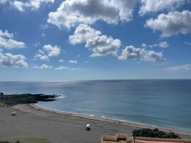 a view of a beach with the ocean and clouds at Pópulo Mar in Ponta Delgada