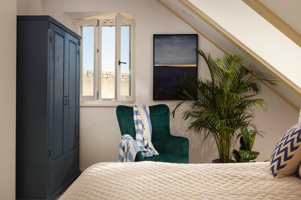 ein Schlafzimmer mit einem Bett, zwei Stühlen und einer Pflanze in der Unterkunft Stayeva 11 in Dubrovnik