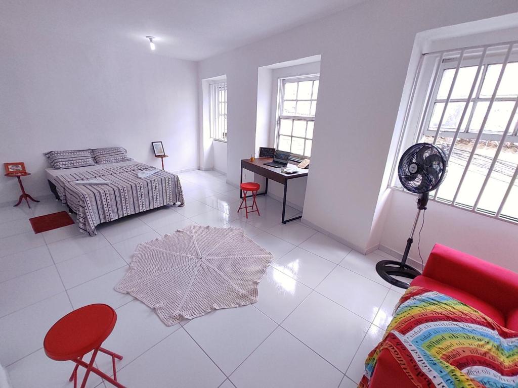 a white room with a bed and a desk with a fan at São Francisco Aparts in Salvador