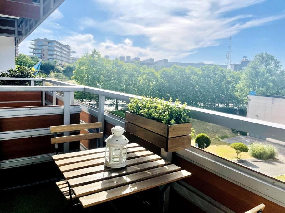 Una botella de cristal sentada en un banco de madera en un balcón en Airport Expo Apartment, en Lisboa