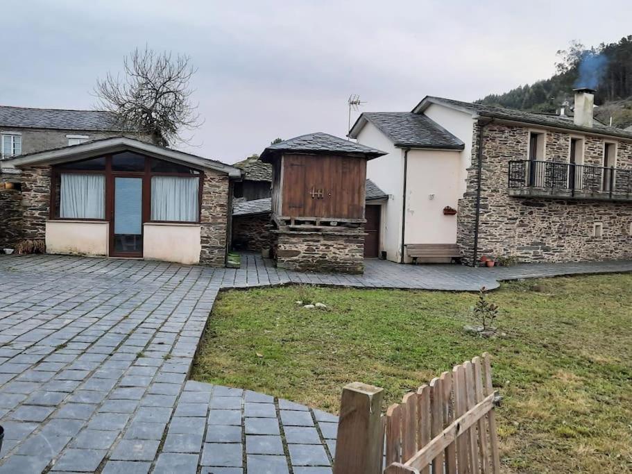 una casa de piedra con una valla y un patio en A casa do Val, en Lugo