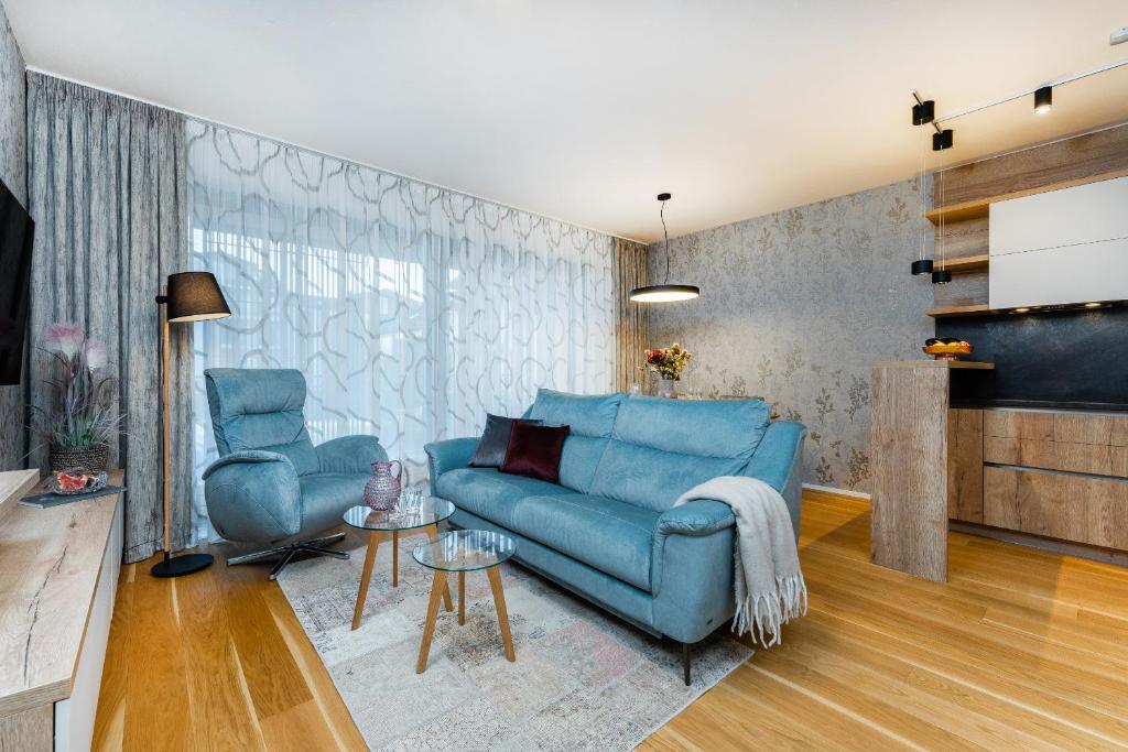 sala de estar con sofá azul y 2 sillas en Apartament A121 Molo Lipno s infrasaunou - Residence Koubek, en Lipno nad Vltavou